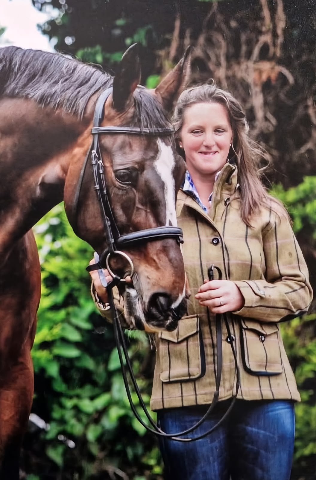 Sally McDerby standing with a bay horse in a bridle